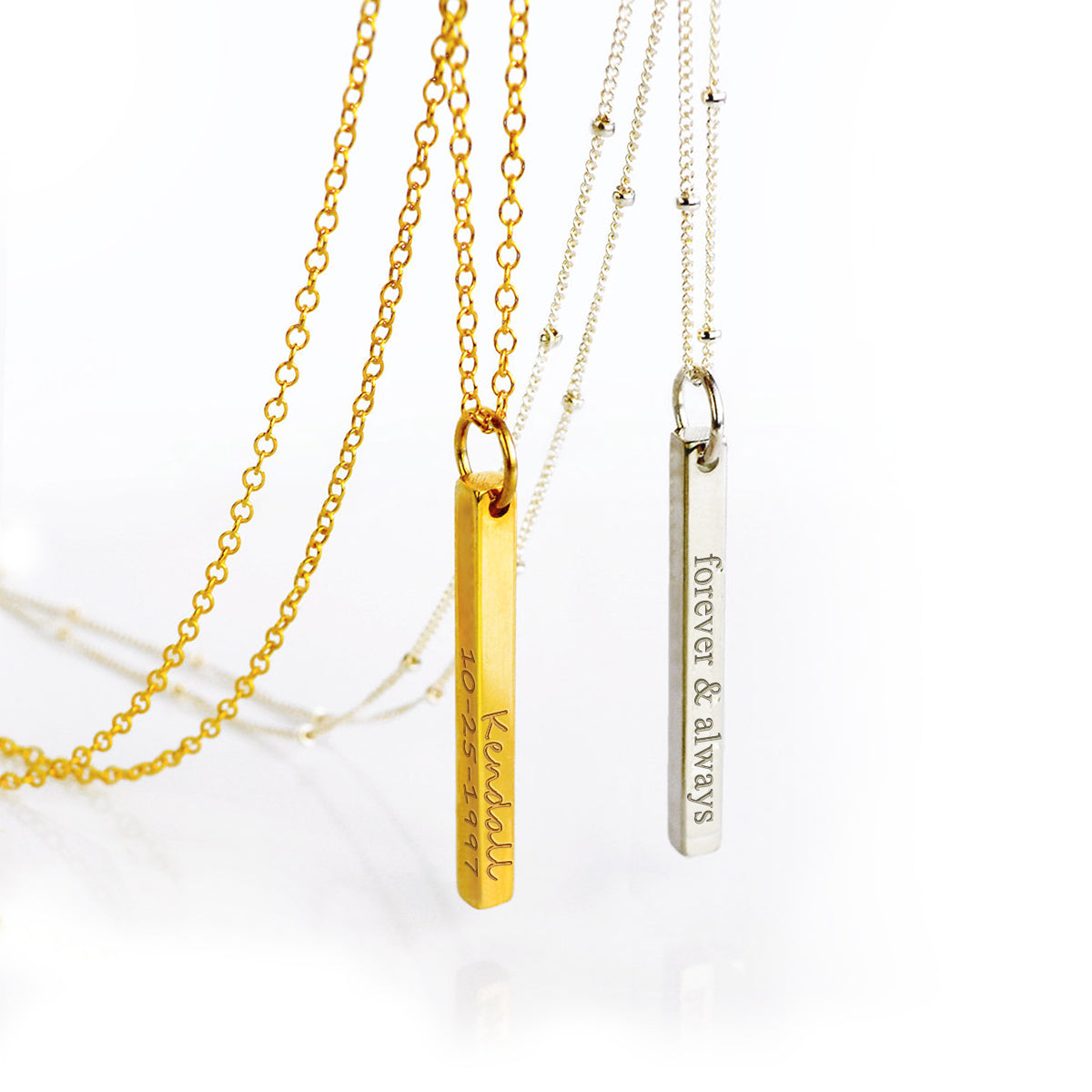 One gold filled dainty bar pendant on a cable chain with name and a special date engraved in our handscript writing. One silver dainty bar pendant on a satellite chain with a phrase and roman numerals engraved in our classic font style