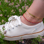 Model is stylishly layering our anklet collection in gold filled. The paw print bar anklet has a stock print with name engraved.