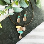 Rose Gold Two Tone Abstract Earrings with Teal and Brown and hook backings paired with matching necklace on black stone background