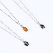 Oval natural Sunstone Cabochon, Black Star Sapphire and Black Copper Obsidian Bezel Set into a 925 Sterling Silver Pendant Plated in 18k Vermeil Gold sitting on a 14K Gold Filled Cable Chain resting on a white background. Great as a gift for fall lovers and orange color and sunstone lovers.