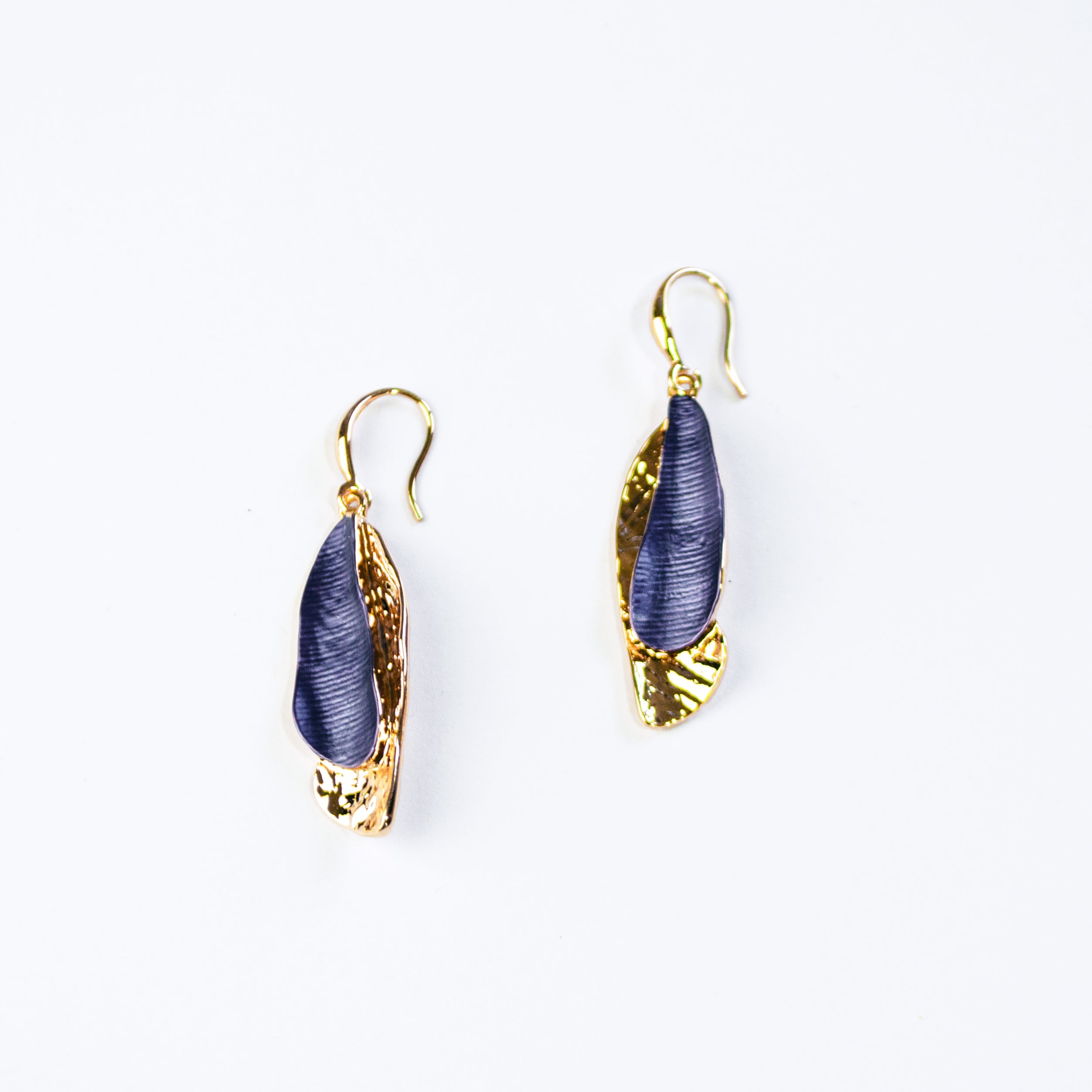 Hook Back Drop Earrings with pendants made of two overlapping textured organic shaped bars with the bottom bar plated in yellow gold and the top painted in blue enamel sit against a white background