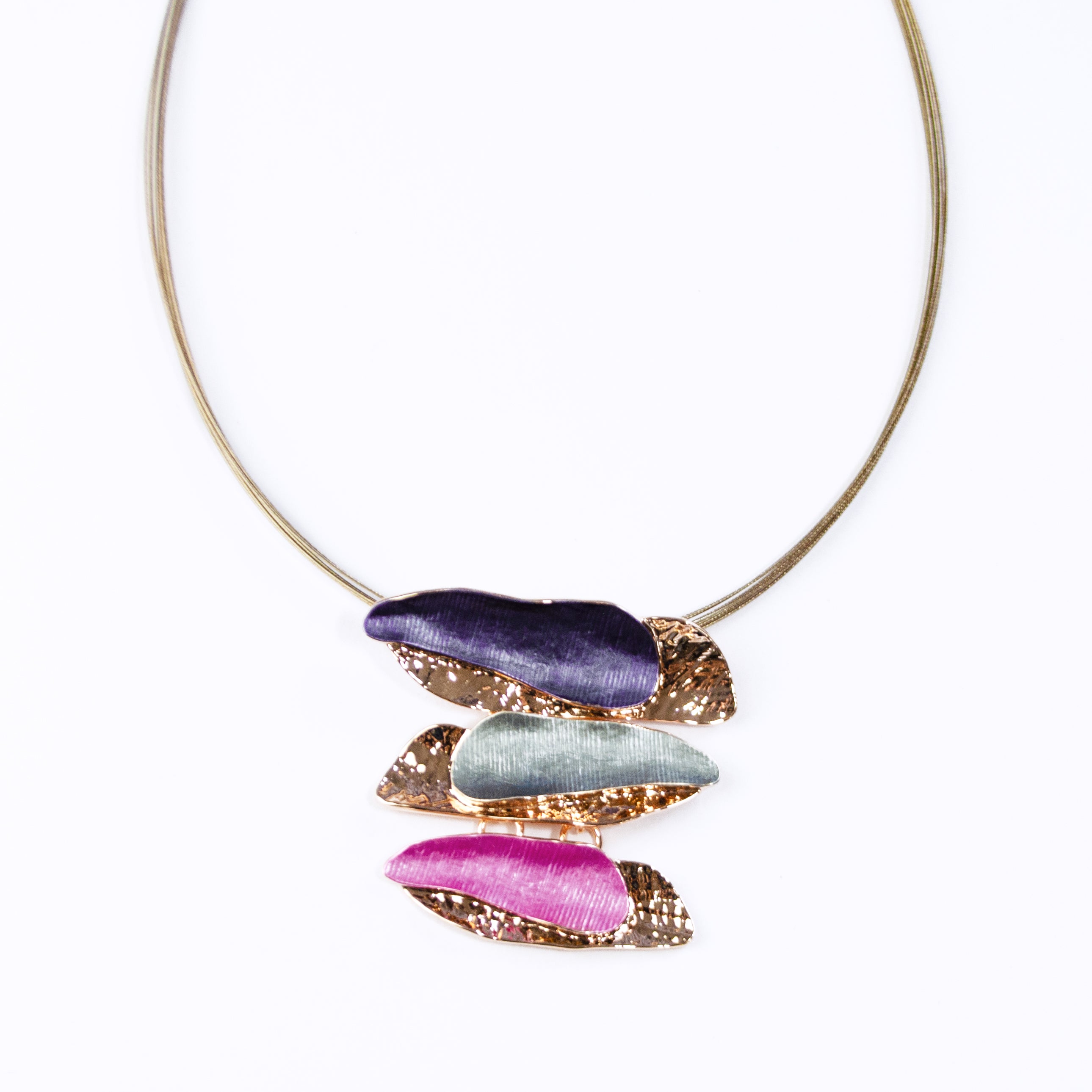 Adjustable Necklace with a brown steel wire chain and a rose gold plated pendant made of three sets of two overlapping long organic bar shapes with the top painted in enamel of either purple, gray, or pink. Necklace sits against a white background.