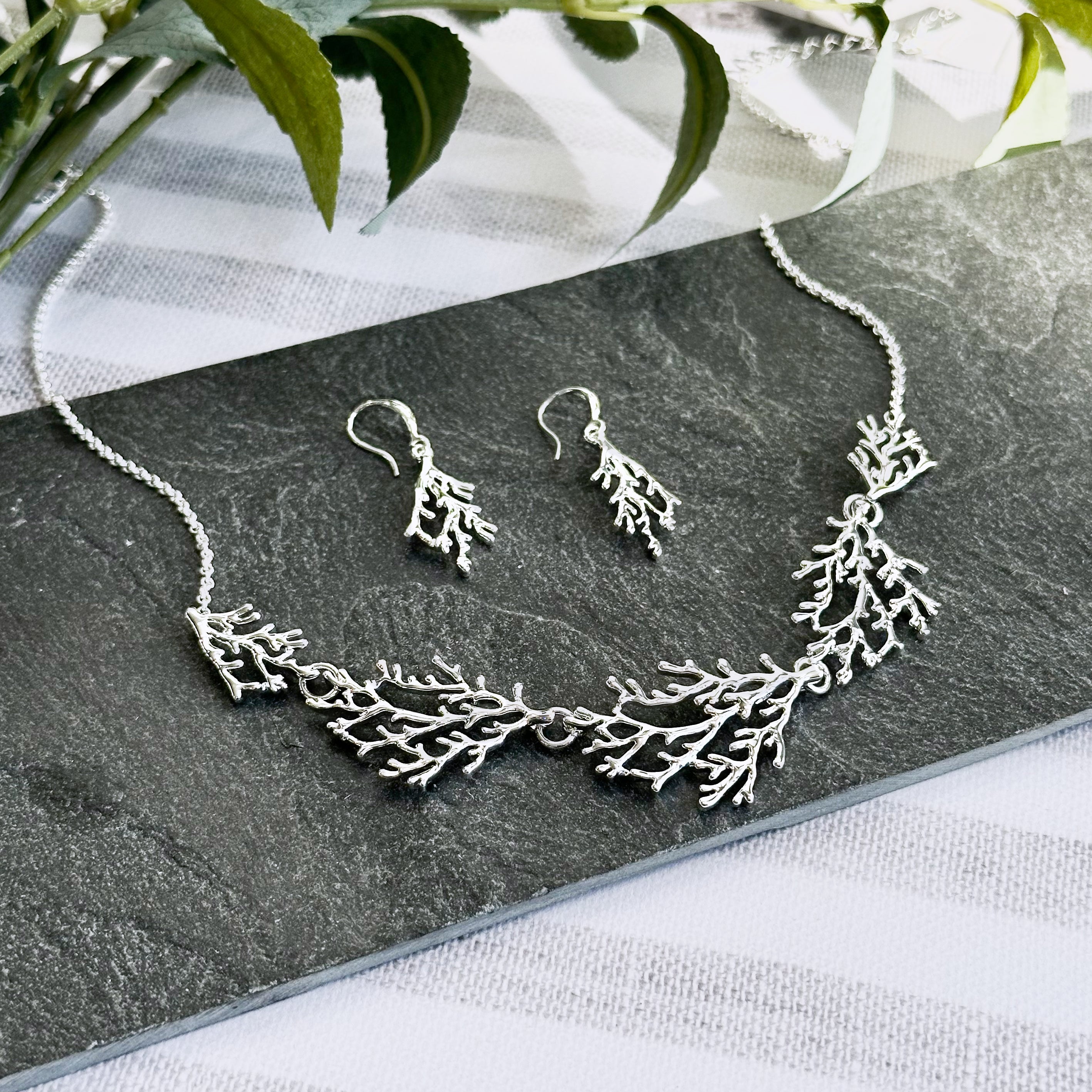 Silver Coral Necklace and Earring Set rest on a dark stone. Summertime Jewelry Set, Beach Lover Jewelry, Ocean Jewelry.