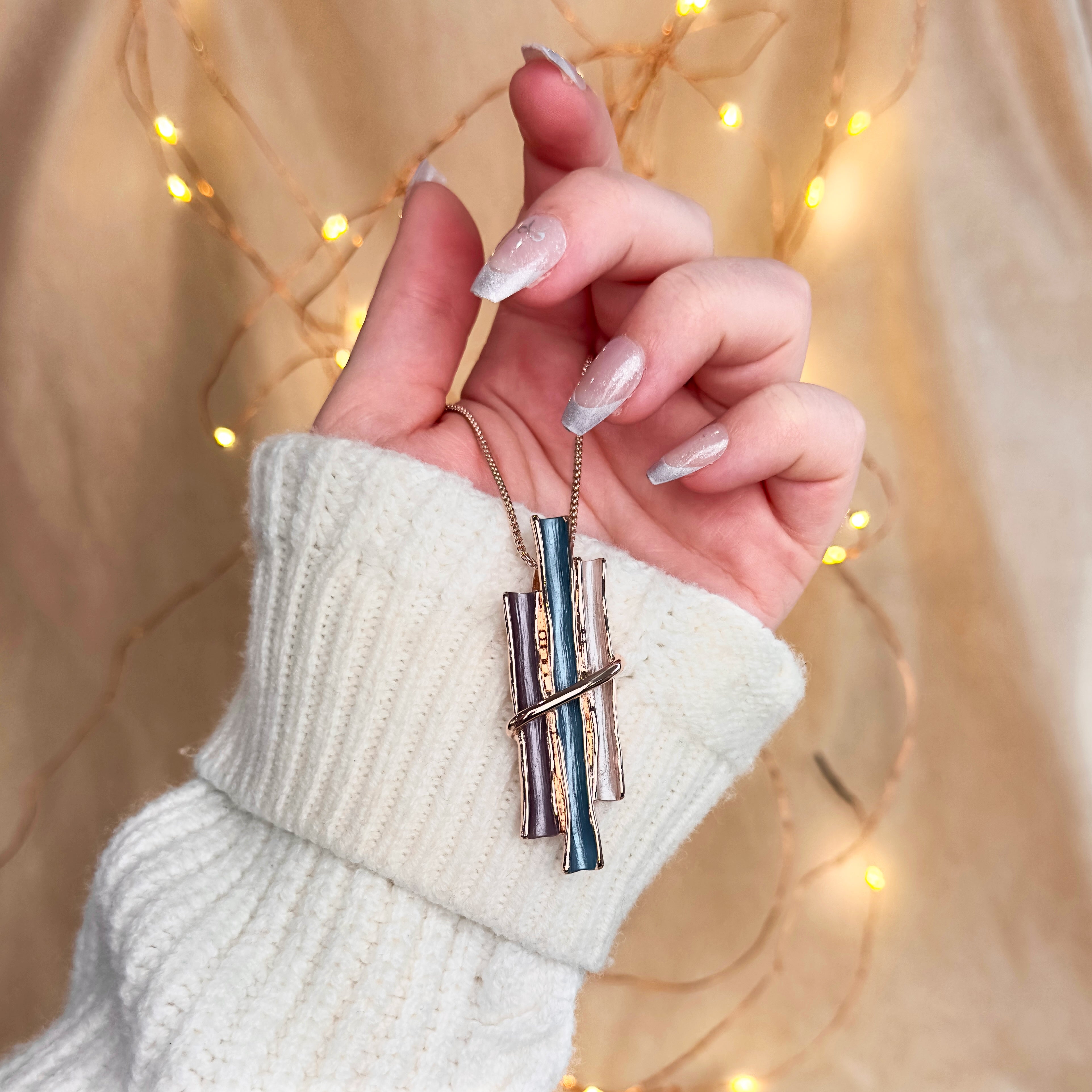 model holding the Rose gold boho style geometric branch pendant necklace on beige background. statement jewelry, statement boho necklace, purple, blue, gray, rose. bohemian jewelry