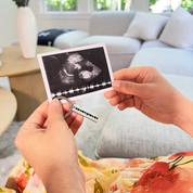 A mom holds a keychain with her childs sonogram engraved. She is also holding a photo of an ultrasound with the sonogram visible on the photo. Personalized baby keychain, baby heartbeat keychain, sonogram keychain, engraved baby keychain 