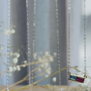 The camera pans down to reveal three multi stone bar necklaces with different birthstone amounts and combinations. A person wears a small two stone necklace on a short chain. Two hands show engraved initials on the top of the necklace, one initial above each stone. A person opens a red danique jewelry gift box revealing a four stone necklace inside. A person shows the number 4 engraved on the bottom of the necklace. Perfect Christmas gift, Mother's day gift or anniversary gift for grandma, mom or wife.