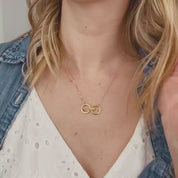 Video of model in white top wearing our open circle geometric eden necklace in gold with two circles and ruby and citrine birthstones.