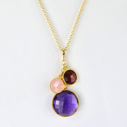 Single gold filled cable chain mothers birthstone round cascade necklace featuring large purple amethyst and garnet and pink chalcedony birthstones representing the children on a white background. 