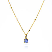 Oval natural tanzanite Cabochon Bezel Set into a 925 Sterling Silver Pendant Plated in 18k Vermeil Gold sitting on a 14K Gold Filled Cable Chain resting on a white background. Great as a gift for fall lovers and sophisticated blue color and sunstone lovers.