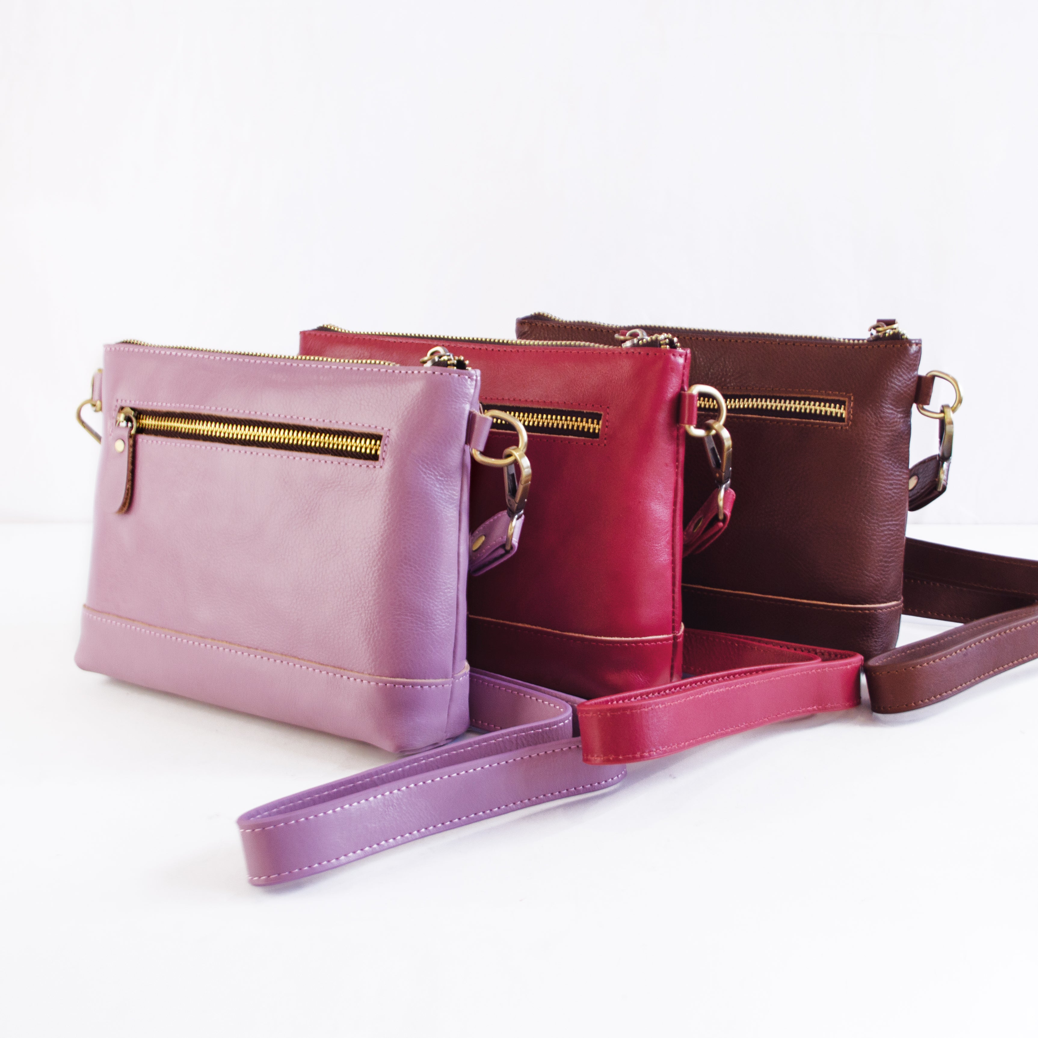 Genuine Leather Crossbody Purses in Light Purple Lavender, Dark Pink Raspberry, and Dark Brown Espresso each have a pocket on the outside of the bag and two pockets on the interior.