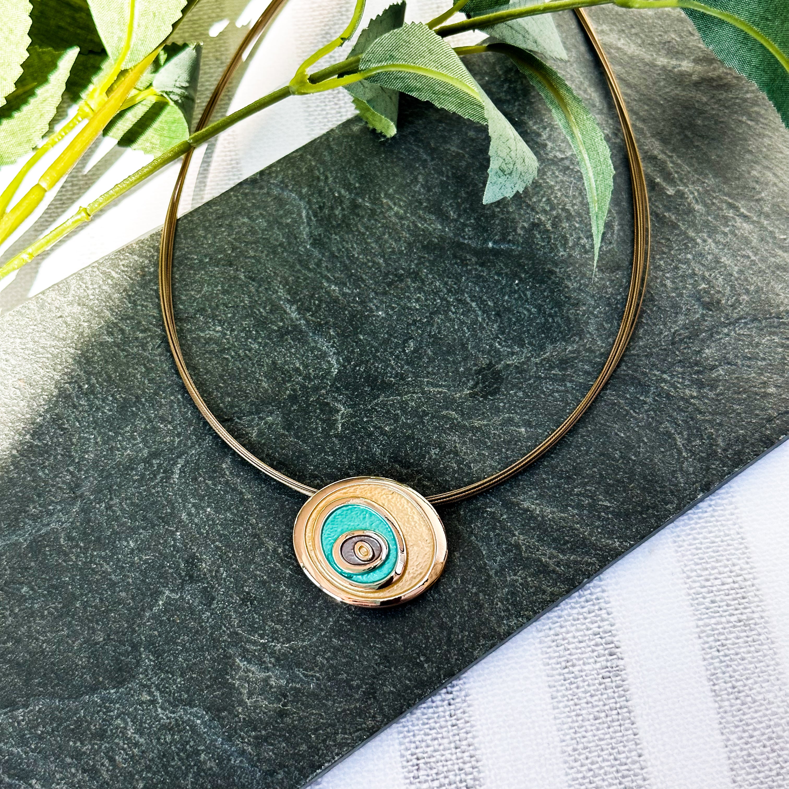 A rose gold and teal necklace on a steel wire cable chain with matching earrings against a black granite background. Teal and rose gold abstract statement necklace, abstract rose flower necklace, bohemian flower jewelry, boho natural earthy jewelry