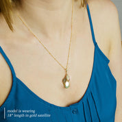 A person in a blue shirt wears a cascading necklace with birthstones and name tags visible. The necklace features the October birthstone, the June birthstone and the March birthstone. 