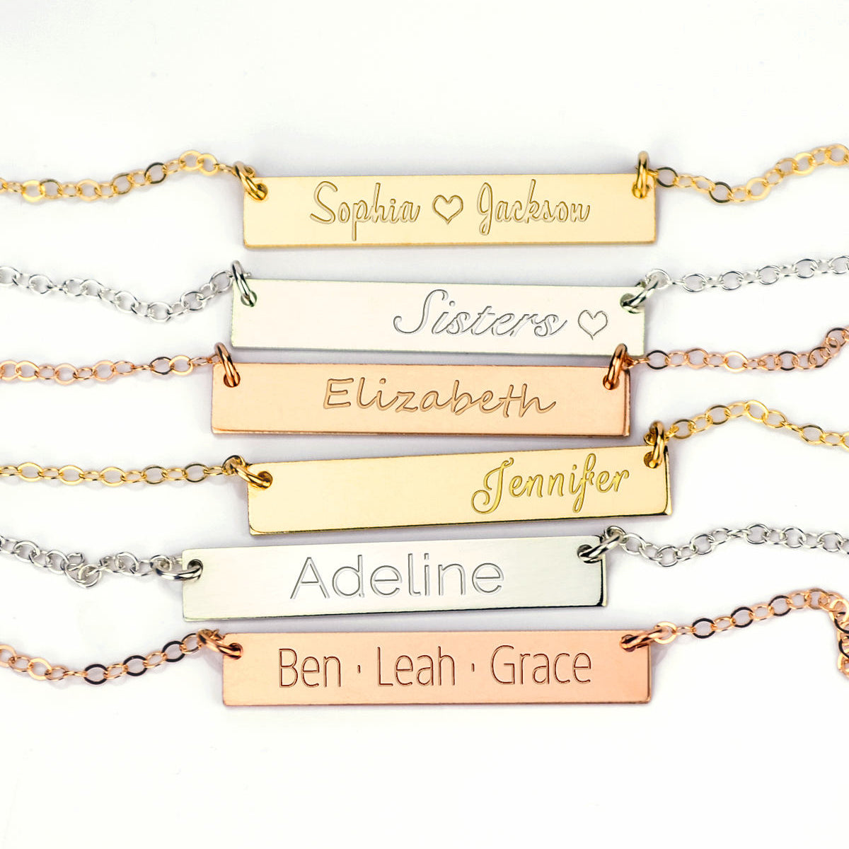 A set of assorted bar necklaces in gold, silver and rose gold against a white background. Customized name necklaces in multiple fonts, swirly name necklace, simple name necklace, custom nameplate necklace