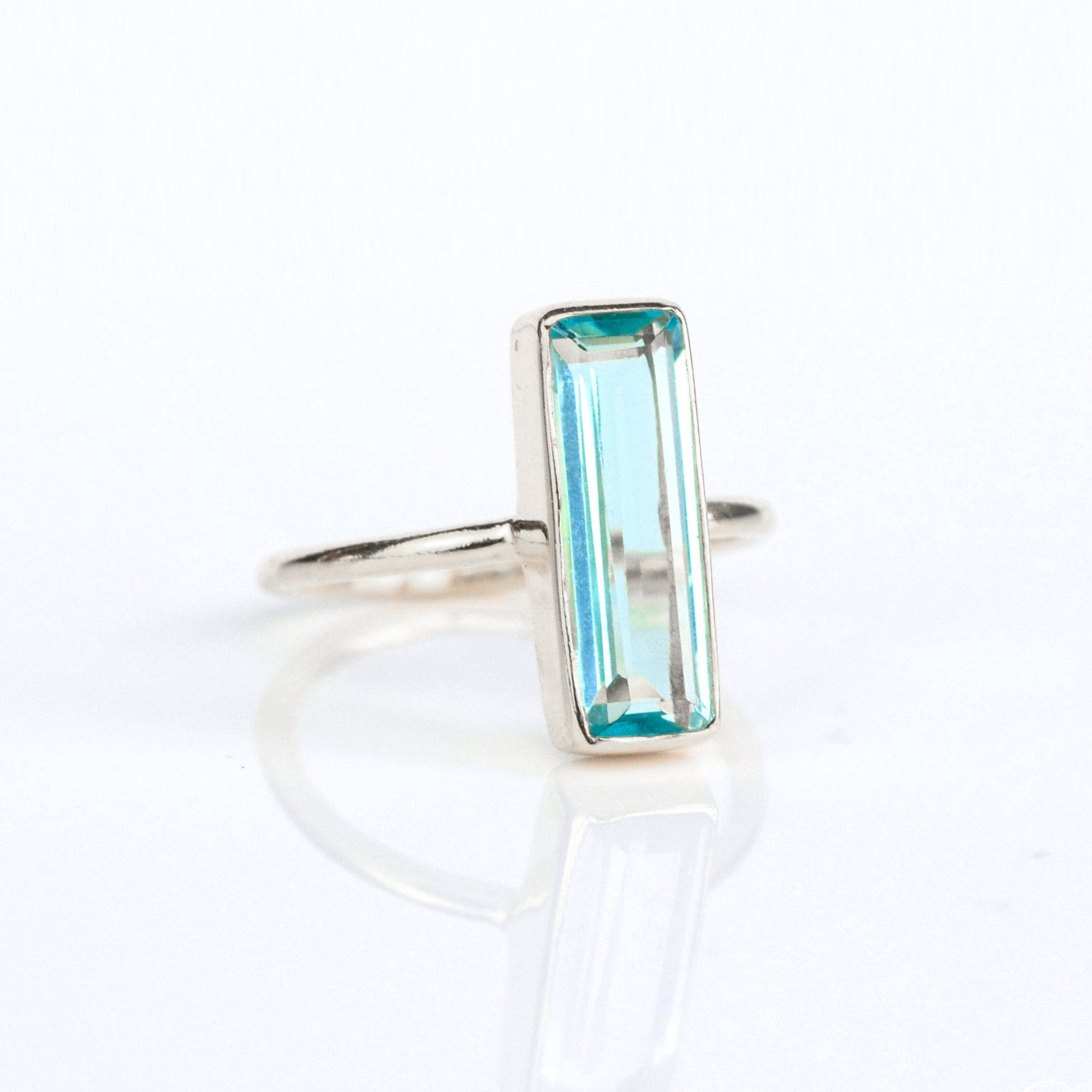 Blue Topaz gemstone ring, December birthstone, striking blue Topaz, unique bar design, minimalist Topaz ring, bezel-set gemstone, Adira Series, fashionable blue jewelry, elegant Topaz ring, eye-catching accessory