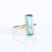 Blue Topaz gemstone ring, December birthstone, striking blue Topaz, unique bar design, minimalist Topaz ring, bezel-set gemstone, Adira Series, fashionable blue jewelry, elegant Topaz ring, eye-catching accessory