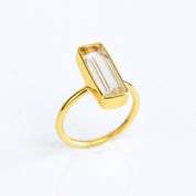 A gold clear quartz bar ring shows April birthstone. Alternative to diamond, custom gemstone ring, april birthstone ring diamond alternative, custom april birthstone bar ring, personalized crystal ring, modern crystal ring, minimalist quartz ring, healing crystal ring, high vibration gemstone ring clear quartz