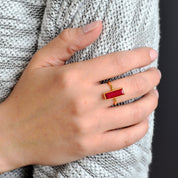 A person in a gray sweater holds their arm, their hand showing off a dyed ruby gemstone bar ring. Custom ruby ring, July birthstone ring, personalized july ring, ruby birthstone jewelry