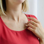 A person in a red shirt wears a dainty adira gemstone ring. Adira tiny gemstone bar ring, small birthstone ring, silver gemstone bar, gold bar ring, rose gold gemstone ring, dainty fashion ring, minimalist bar ring, chic gemstone jewelry, custom gemstone accessory, delicate bar ring, elegant petite ring