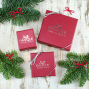 3 red Danique Jewelry boxes with silver bows rest on a white background with flowers along the edges of the image. Each bracelet comes in a gift-ready box ready to be handed off to the recipient immediately, or to be delivered directly to them.