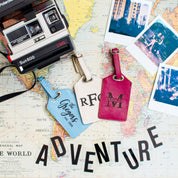 3 luggage tags on a world map with the word Adventure at the bottom and a camera and polaroids in the upper corners. Travel junkie gift, honeymoon gift for newlywed couple, travel gift for newlyweds