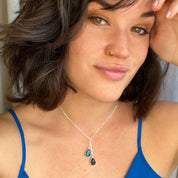 A person with a blue shirt and brown hair wears a blue lariat necklace. Lariat birthstone necklace, custom birthstone jewelry, cascading gemstone necklace, gold lariat necklace, silver lariat necklace, rose gold lariat, personalized birthstone pendant, multi-gemstone necklace, elegant gift for mom, custom family necklace, birthstone jewelry