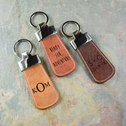 Three custom engraved leather paddle keychains. Honey keychain with formal monogram. Cinnamon keychain with phrase ready for adventure. Espresso custom keychain with initials and a special date