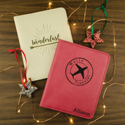 Two Personalized Genuine Leather Passport Holders made with full grain leather in the colors Nude - an off-white, and Raspberry - a dark pink. Each Personalized Travel Wallet is engraved with an image and a name.