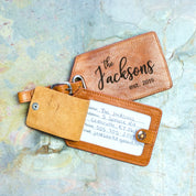 A honey luggage tag engraved with the Family monogram sits on a granite background. The back flap is open revealing a card with information written on it.Family Name Engraving Luggage Tag With ID Card Window Light Brown Leather Color natural leather travel bag tag, identification tag for luggage