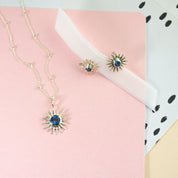 Matching Sun Burst Necklace and Stud Earring Set resting on a pink paper with a white ribbon. 3mm Blue September Birthstone Kyanite bezel set Sterling Silver Sun Stud Earrings with matching 5mm Kyanite Sun Burst Sterling Silver Pendant on a Sterling Silver Cable Chain. September Birthday Gift, Jewelry Set for Her, summer jewelry set, sun jewelry set